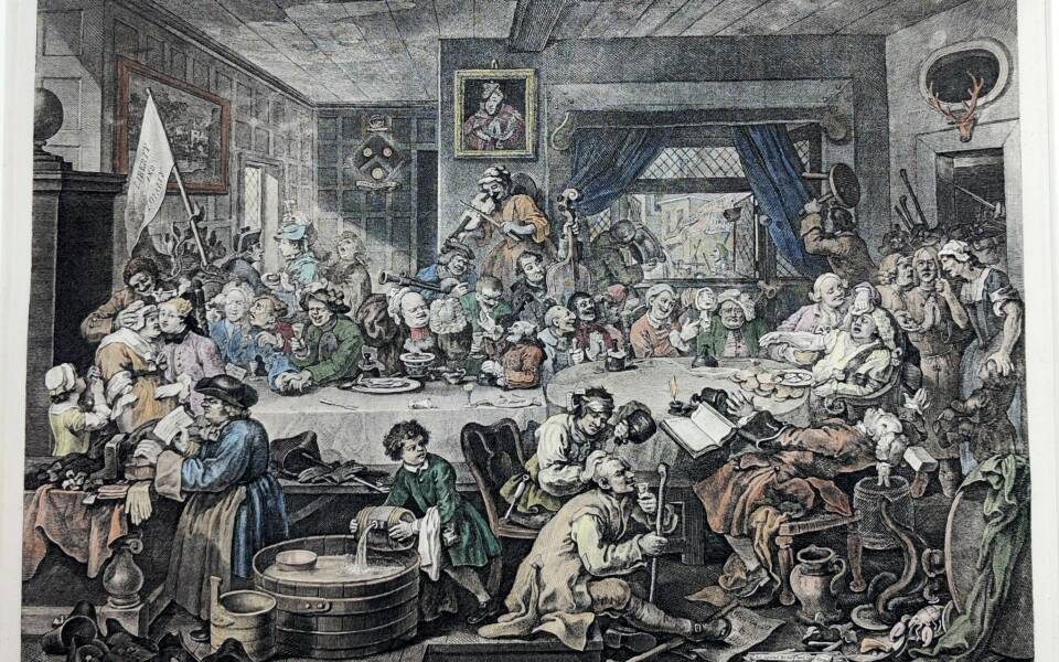 An Election Entertainment. A raucous dinner party around a huge table. Outside the window a protest is visible.