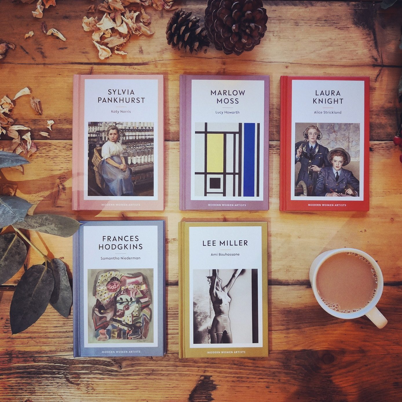 Photograph of the range of five Eiderdown Press books on a wooden floor next to a cup of tea.