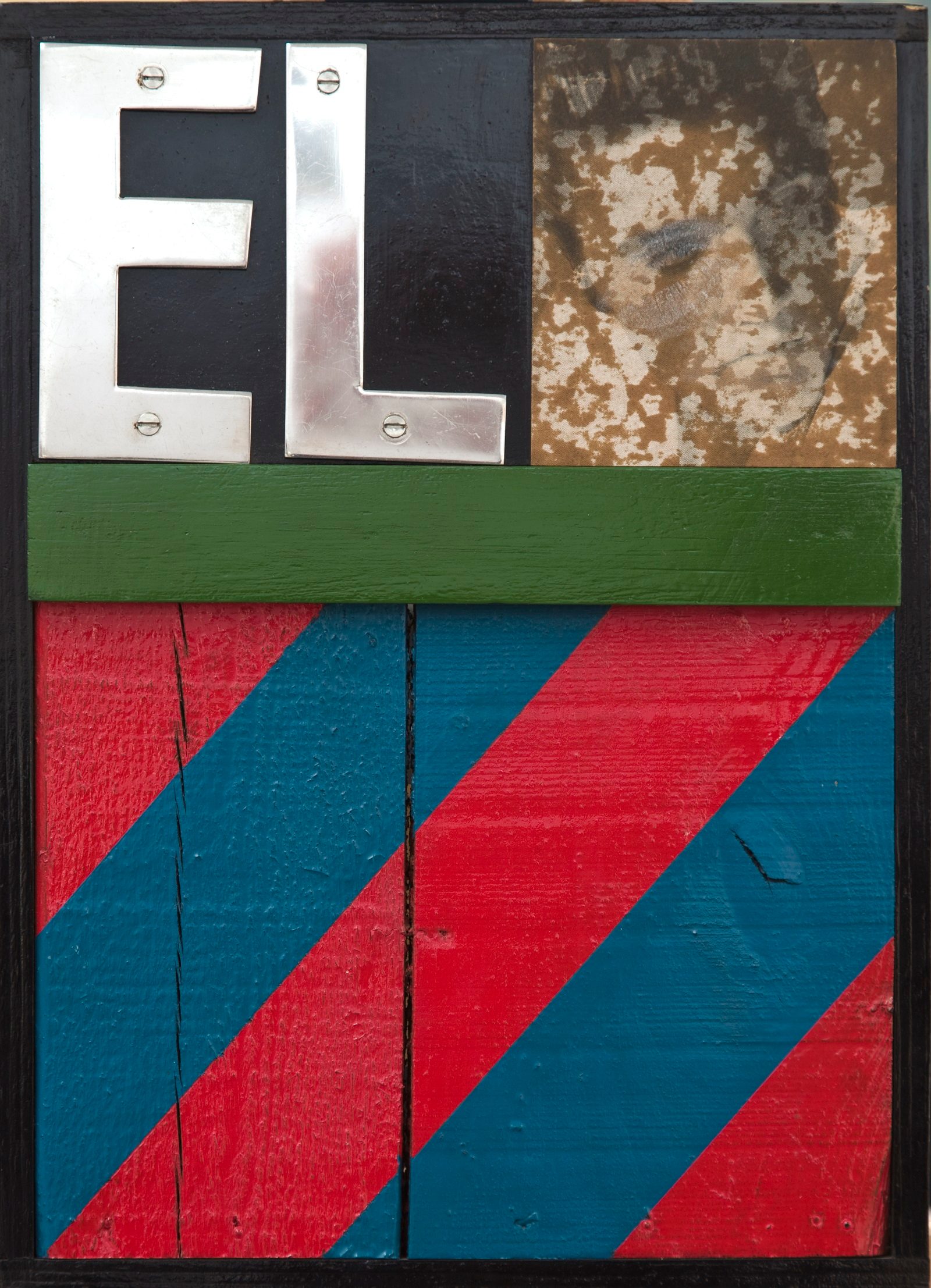 Wooden boards painted with red and blue diagonal stripes oin the lower half. In the top left corner are the letters E and L and in the right corner there is a distressed photograph of Elvis Preslet smeared with lipstick